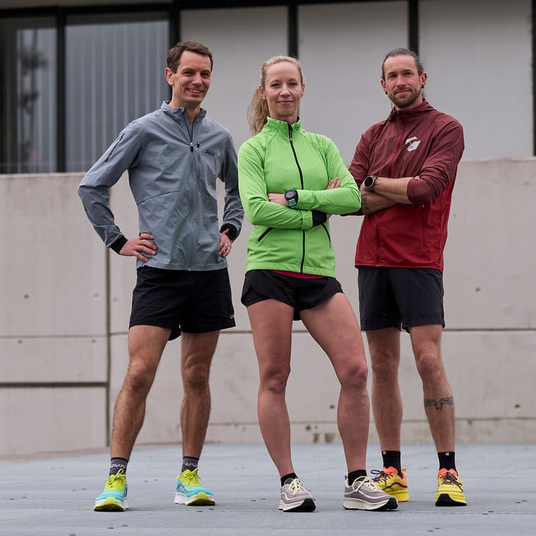 Drei Joe Nimble Athleten stehen nebeneinander und zeigen ihre Laufschuhe